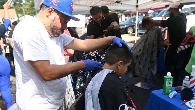 Volunteer Bobby Ceba gives haircuts to children at the East...