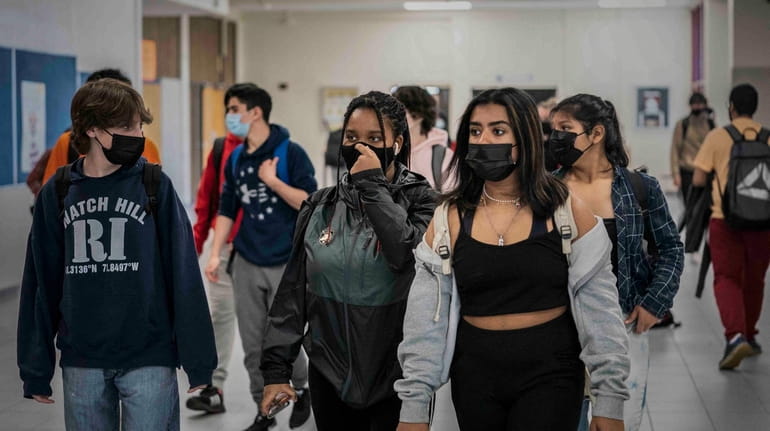 High school students walk between classes on April 22 wearing their masks...