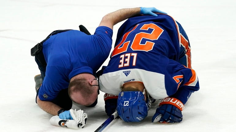 A trainer tends to Islanders left wing Anders Lee, who had...