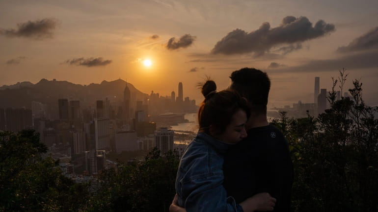Visitors look at sunset from a hill in Hong Kong,...