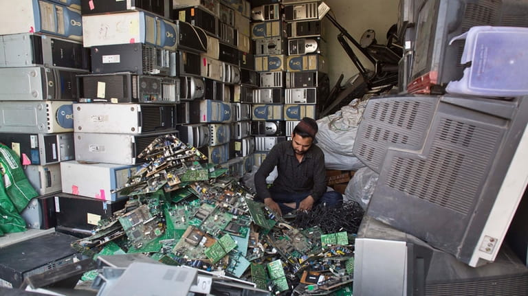 An Indian man works at a electronic waste recycling shop...