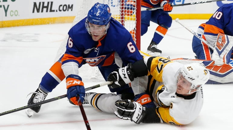 Islanders defenseman Ryan Pulock and Penguins center Sidney Crosby battle...