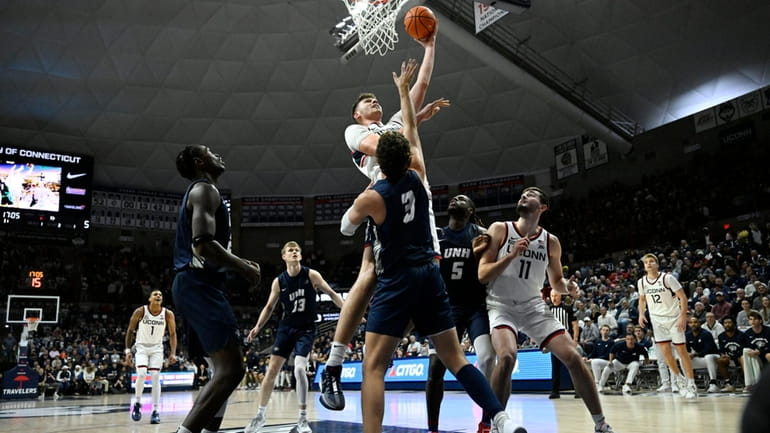 UConn center Donovan Clingan, top, makes a basket over New...