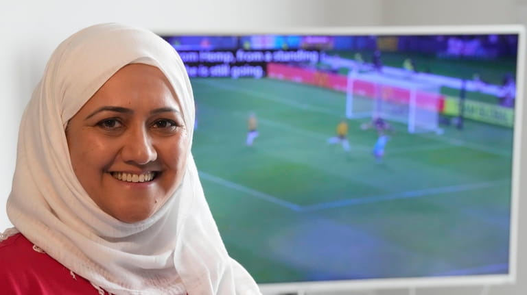 Huda Jawad smiles in front of her TV showing highlights...