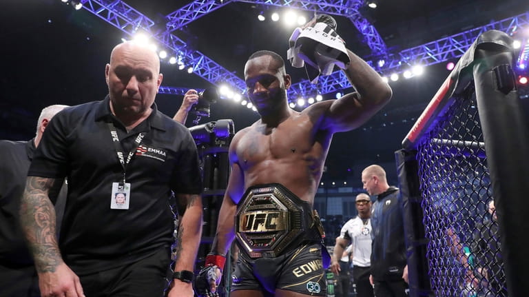 Leon Edwards, right, leaves the Octagon after victory against Kamaru...