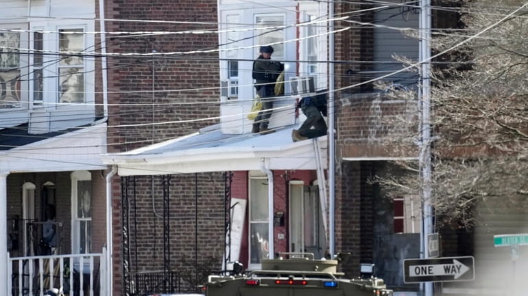 Police surround a home in Trenton, N.J., Saturday, March 16,...