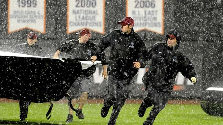 Grounds crews scramble to cover the field as rain pours...