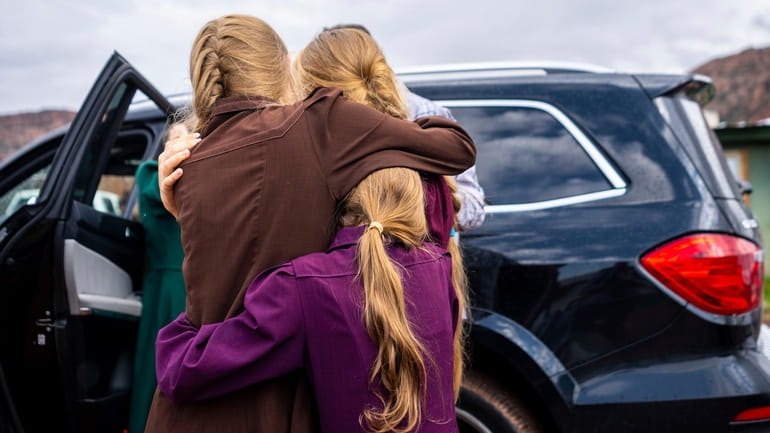 Three girls embrace before they are removed from the home...