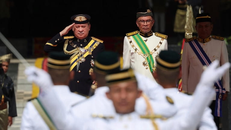 Sultan Ibrahim Sultan Iskandar, left, salutes the guard of honor...