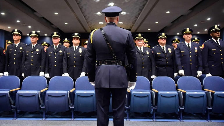 Nassau County police officers stand at attention in the auditorium...