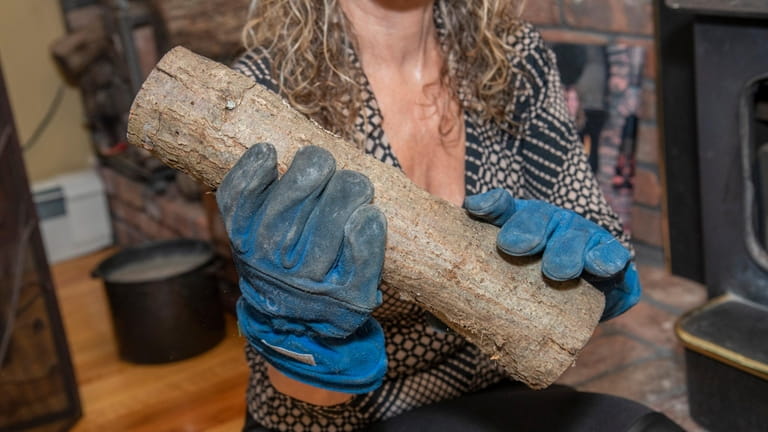 Enza Brandi wears heat-resistant gloves to load wood in the fireplace.
