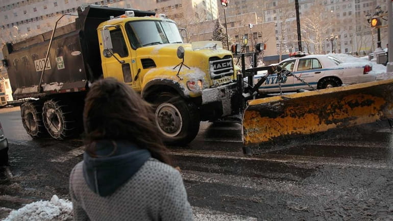 A woman watches a snowplow scrape Court Street in Downtown...