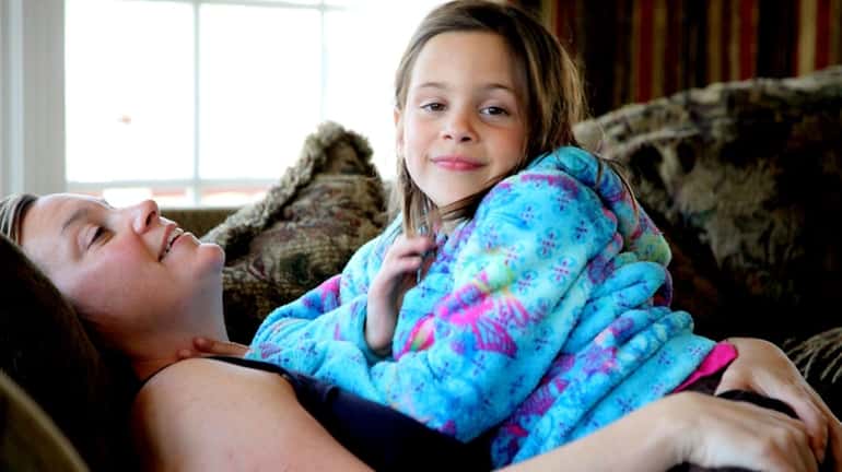 Katie Trebing, 7, sits with her mom at home in...