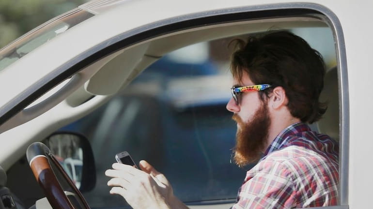 An man works his phone as he drives through traffic...