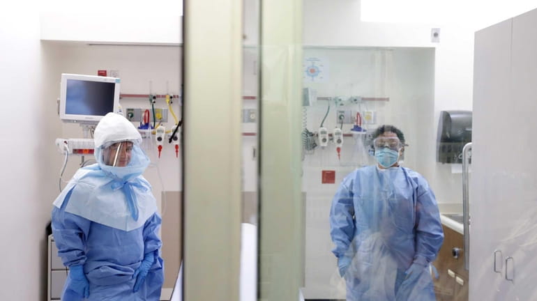 A medical worker wears a protective suit inside an isolation...
