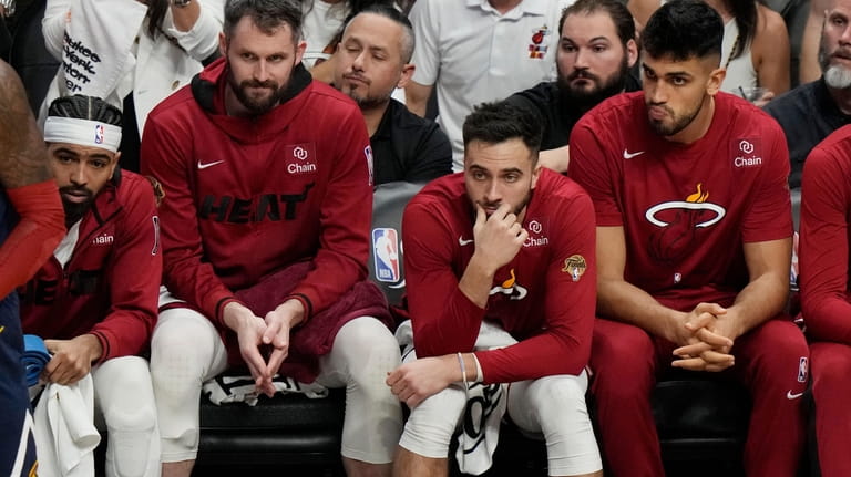 Miami Heat players sit on the bench as the team...