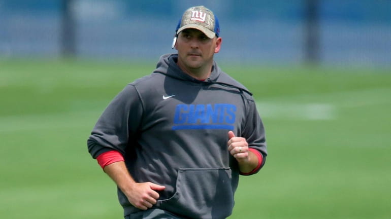 New York Giants head coach Joe Judge runs between fields...