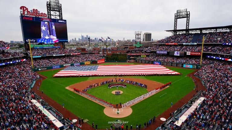 The Philadelphia Phillies and the Cincinnati Reds stand for the...