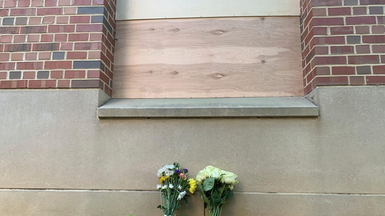 Flowers lay under a boarded up window at Caudill Labs...
