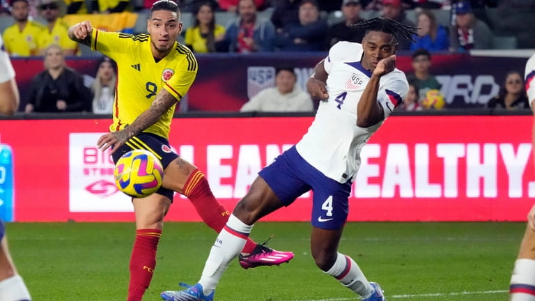 Colombia's Cristian Arango, left, takes a shot on goal next...