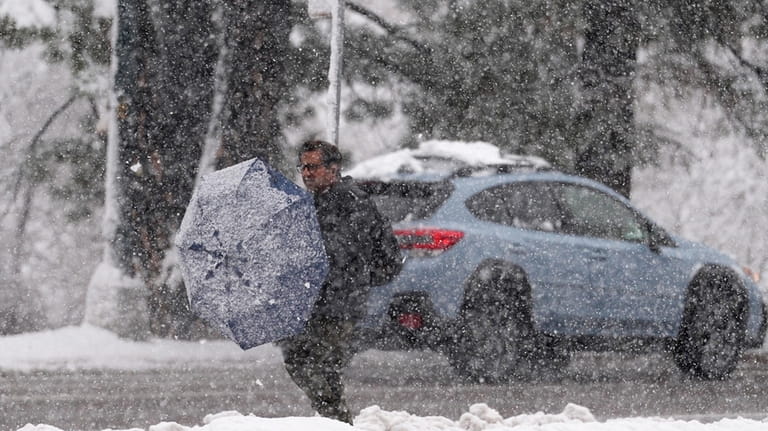 A pedestrian cleans off his umbrella while waiting for a...