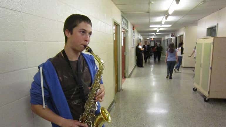 Junior David Barton, 17, practices on his saxophone backstage before...