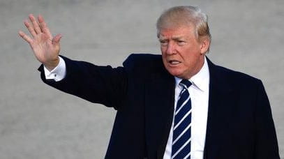 President Donald Trump waves as he walks towards Air Force...