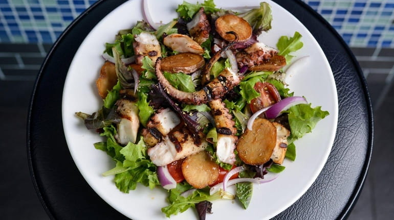 Grilled octopus salad, with tomato, onion, and potato slices on...
