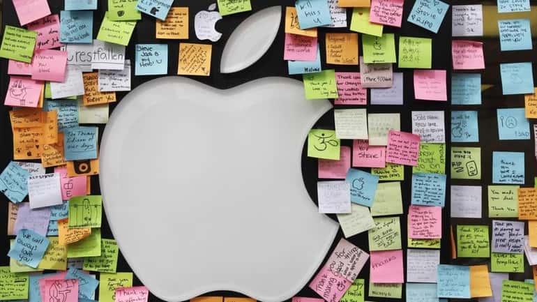 Sticky notes form a memorial to Steve Jobs at an...