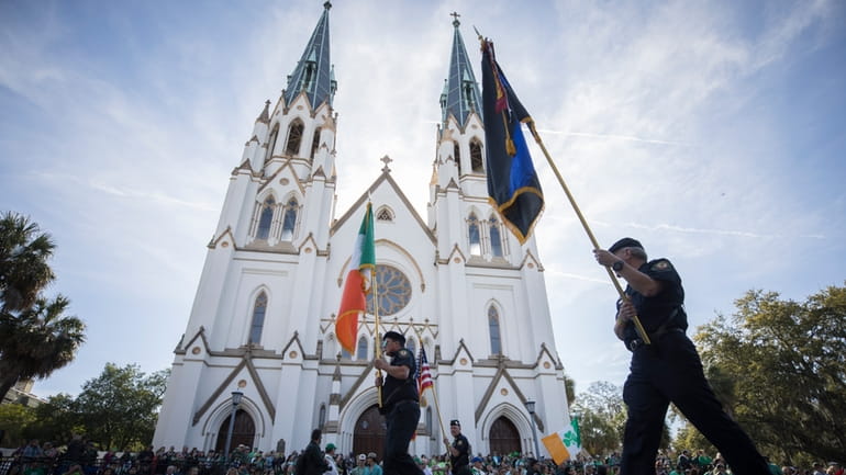 Participants carry flags past the Cathedral Basilica of St. John...