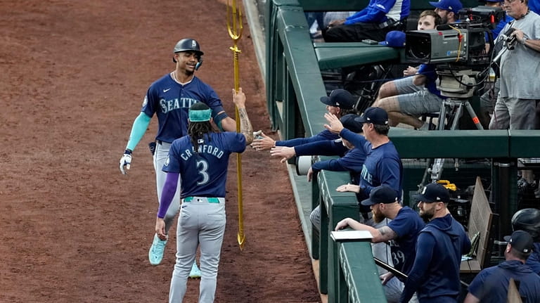 Seattle Mariners' J.P. Crawford (3) gives Julio Rodriguez a trident...