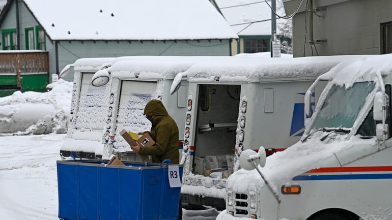 A mail carrier loads a mail truck with mail, March...