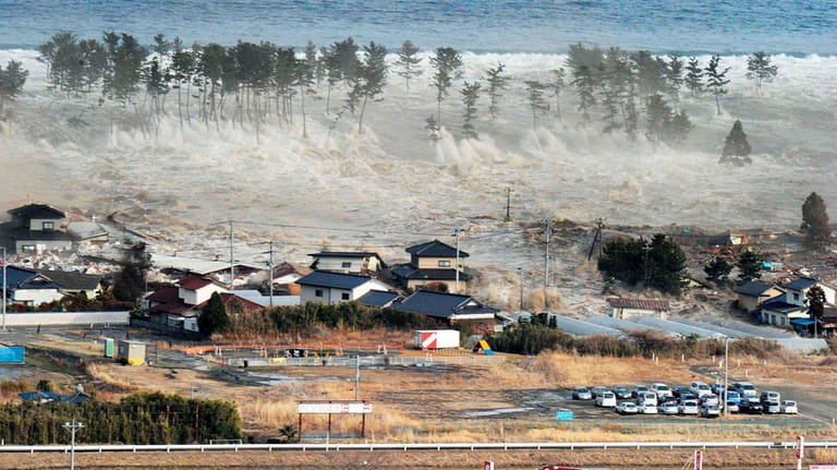 Waves from a tsunami hit residences after a powerful earthquake...