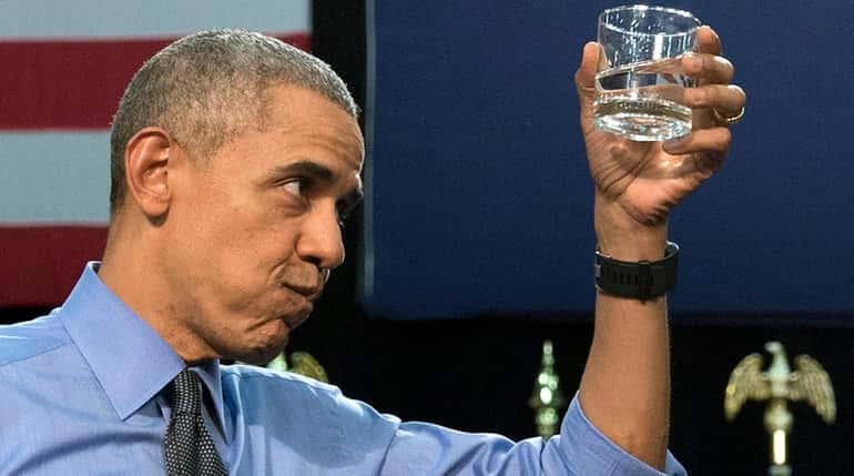 President Barack Obama holds up a glass of water as...