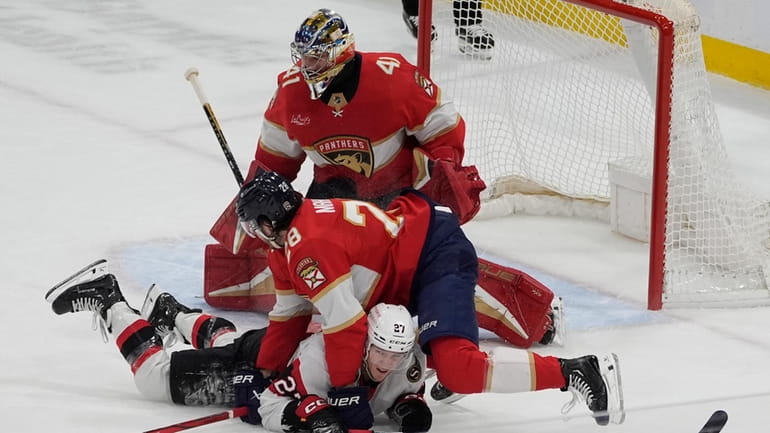 Florida Panthers defenseman Josh Mahura (28) falls on Ottawa Senators...