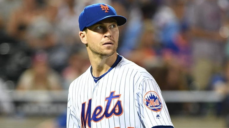 Mets pitcher Jacob deGrom looks up as he walks to...