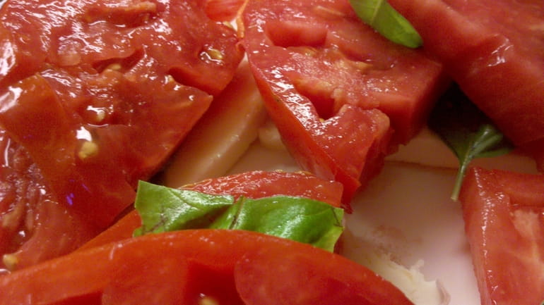 Caprese salad, made by layering slices of fresh tomato with...