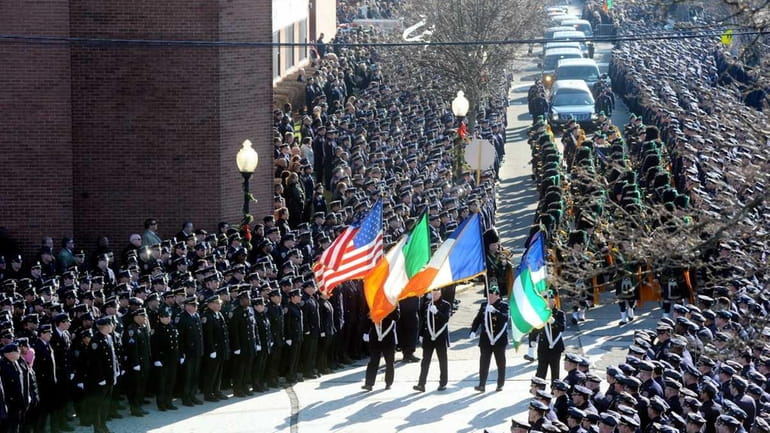 Police officers stand at attention as the funeral procession for...