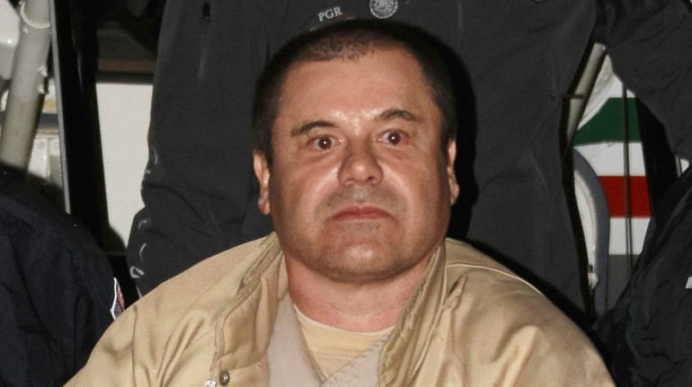 Authorities escort Joaquín "El Chapo" Guzmán Loera to a caravan of SUVs...