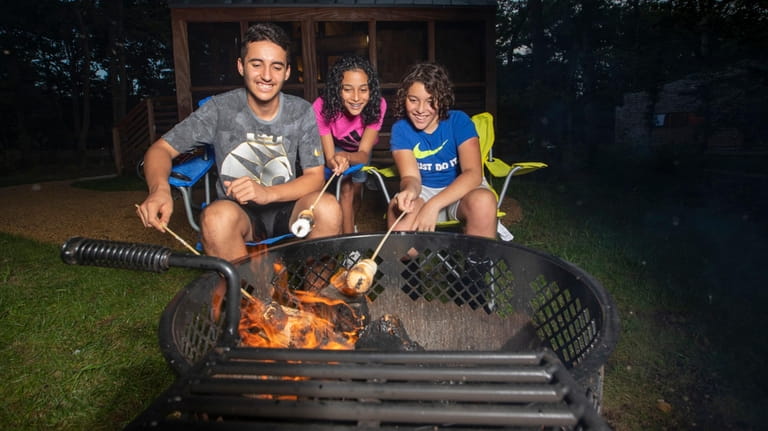 Campers roast marshmallows outside their rented glamping cabin at Wildwood...