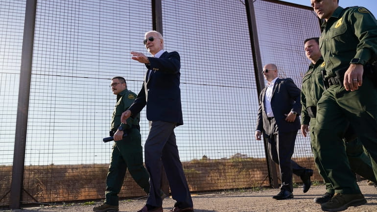 President Joe Biden walks along a stretch of the U.S.-Mexico...