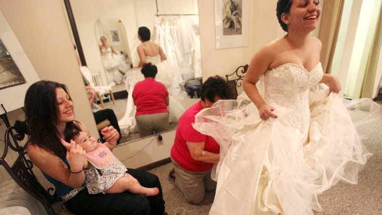 Jessica Vega, right, tries on the wedding gown at Bella...