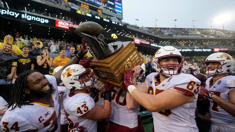 Iowa State players celebrate with the Cy-Hawk Trophy after an...