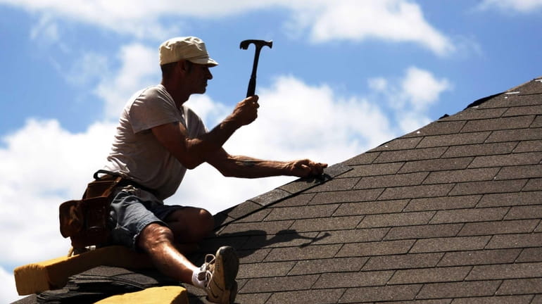 A builder works on a roof of a new house...