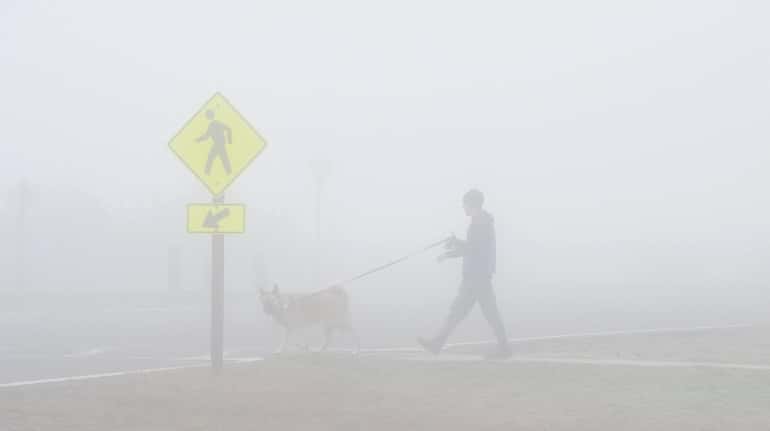 A man walks his dog in thick fog on Sunday...