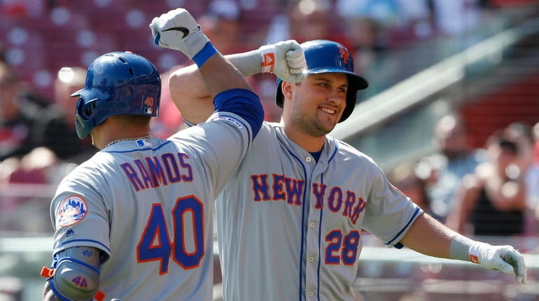 The Mets' J.D. Davis bumps elbows with Wilson Ramos following...