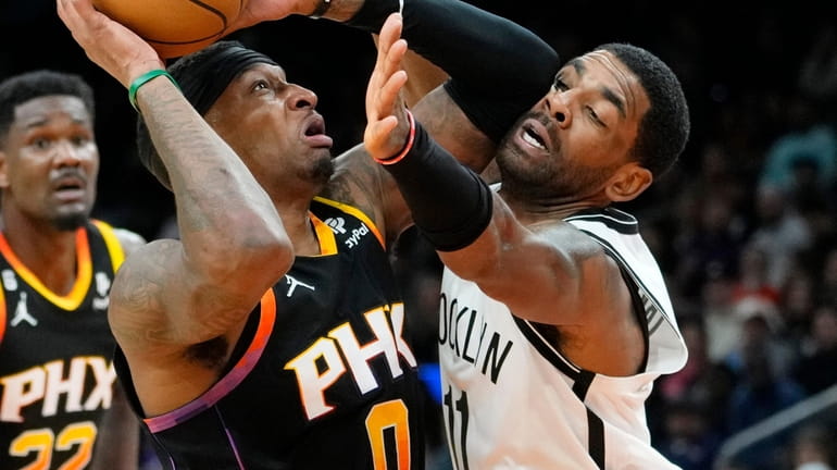 Suns forward Torrey Craig is fouled by Nets guard Kyrie Irving during...