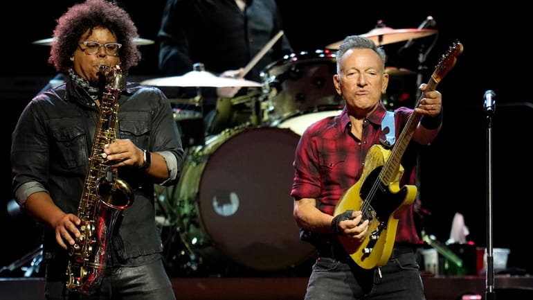 Bruce Springsteen, right, plays his guitar as Jake Clemons plays...