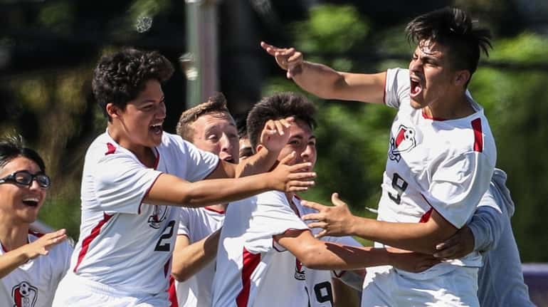 Bellport's Jonathan Cruz (9) is congratulated by his teammates after...