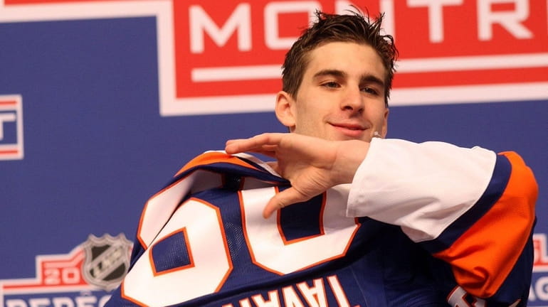 John Tavares puts on his team's jersey after being picked...